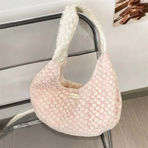 Detail of floral daisy embroidery and lace mesh texture on pink canvas shoulder bag