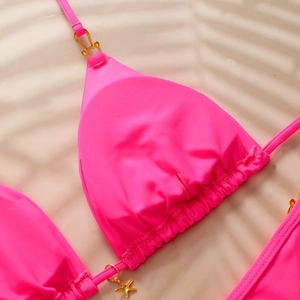 Detail of pink bikini top with gold starfish pendant and soft shadow beach background