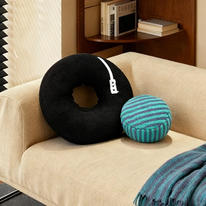 Black record vinyl plush pillow and blue striped ball cushion on a soft fabric sofa