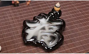 Detail of a black ceramic backflow incense burner with smoke flowing through a Fu character