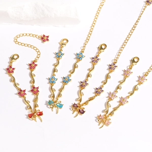 Golden bracelet set with colorful cubic zirconia bow and flower charms on white background