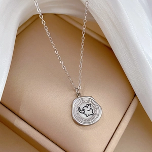 Macro detail of a silver titanium steel necklace featuring a minimalist elephant pendant