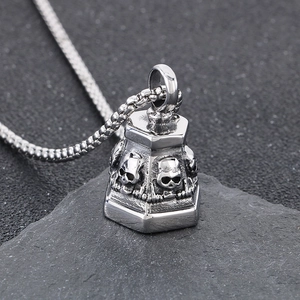 Macro shot of punk style stainless steel skull bell pendant on a stone background