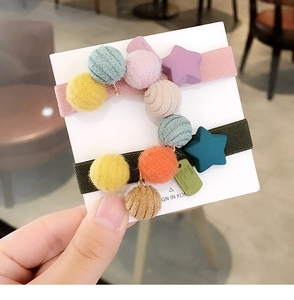 Dettaglio di elastici per capelli in peluche con palline colorate e ciondoli a stella opachi