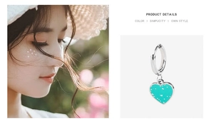 Detail view of heart-shaped hoop earrings in silver finish with blue spotted charm