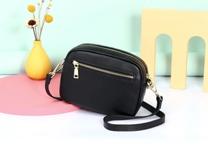 Detail van zwarte crossbodytas van generfd leer met hoogwaardige goudkleurige metalen ritsen