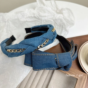 Close-up of blue denim bow headbands with metal chain and yellow stitching details