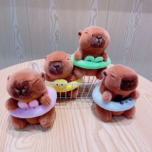 Set of four plush capybara dolls wearing colorful swimming rings on a wooden table