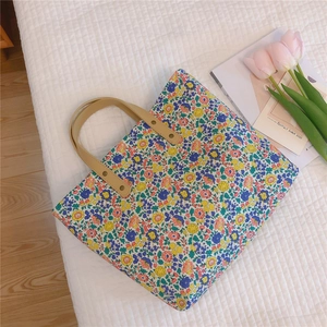 Detailed shot of floral canvas tote bag with leather handles on white textured fabric