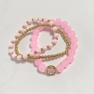 Close-up of pink and gold beaded elastic bracelets with a circular pendant detail