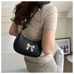 Chic black crescent underarm bag with silver bow detail shown on a model's shoulder