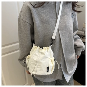 Detail of white nylon bucket bag featuring a drawstring closure and mesh side pocket