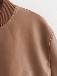 Detail of brown leather bomber jacket showing ribbed collar and premium shoulder stitching