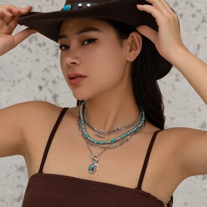Close-up of layered bohemian necklace with turquoise beads and Luck charm on a model
