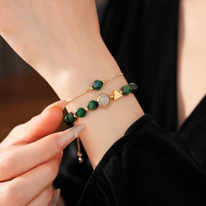 Detail of double-layer green beaded tiger eye bracelet worn on wrist with gold chain