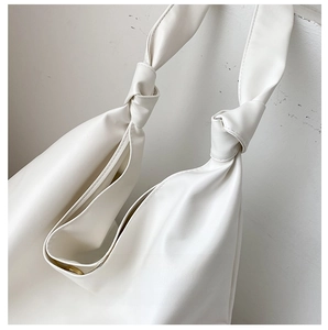 Detail of magnetic snap closure and knotted strap on minimalist cream tote bag