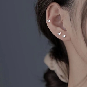 Close-up of minimalist silver butterfly stud earrings on model for a refined jewelry look