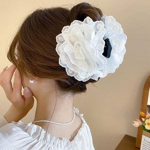 Détail d'une pince à cheveux rose en dentelle blanche sur modèle aux couches élégantes