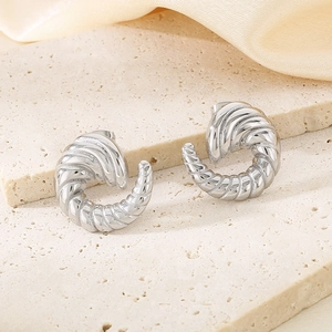 Detail view of silver spiral twist C-shape stud earrings on a textured stone base