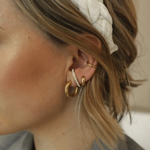 Close-up of model wearing gold S925 silver half-moon pearl stud earrings and ear cuffs