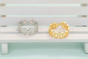 Verstellbare Punk-Gliederkettenringe in Gold und Silber auf einem Mini-Stuhl