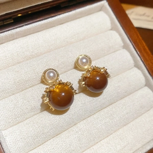 Macro shot of 18K gold plated earrings with amber stone, pearl and crystal details
