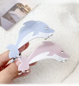 Detailed close-up of blue and pink dolphin hair claws with star rhinestone accents