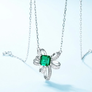 Elegant silver necklace with emerald-green square stone and sparkling bow pendant
