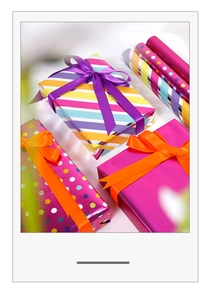 Detail of metallic gift wrap with pink stripes and dots featuring purple satin ribbons