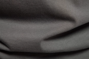 Macro shot of dark grey cotton knit fabric texture with soft folds on long sleeve polo shirt