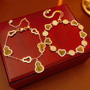 Detail of 18K gold plated bracelet featuring tiger eye gourd and heart charms with zircon