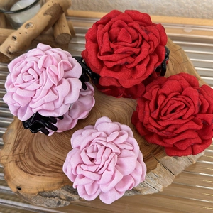 Detail of four fabric rose hair claws in red and pink on a rustic wooden background