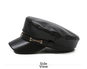 Detail view of black PU leather baker boy hat featuring gold chain link embellishments