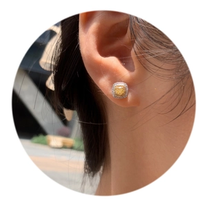 Close-up of square yellow zircon halo stud earrings worn on ear with silver base