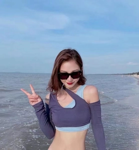 Outdoor close-up of a two-piece blue vest and purple asymmetrical crop top on a beach