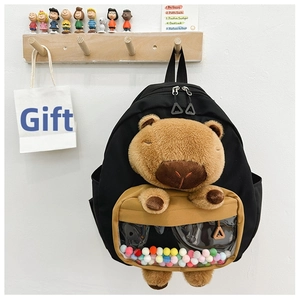 Detail of black canvas schoolbag with 3D capybara plush and transparent pompom compartment