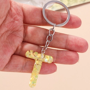 Detailed macro view of resin alphabet T keychain with yellow and green sequins and metal ring