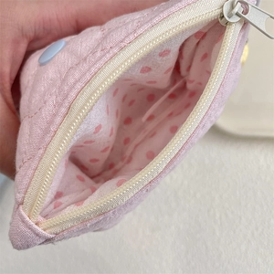Detail of pink quilted coin purse showing zipper closure and pink polka dot lining