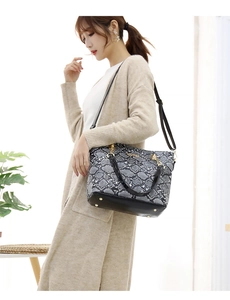 Detail view of snakeskin pattern tote bag with gold hardware and black leather handles