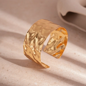 Close-up of golden wide open cuff bracelet with irregular hammered metal texture