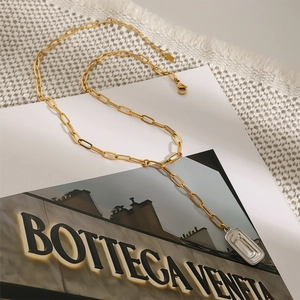 Detail einer goldenen Büroklammer-Halskette mit silbernem rechteckigem Anhänger-Detail