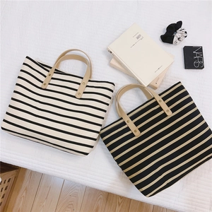 Flat lay of striped canvas tote bags with leather handles and gold rivet accents