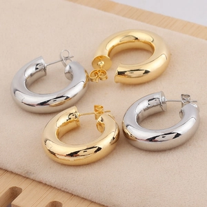 Détail macro de boucles d'oreilles créoles épaisses de 28mm en or et argent polis