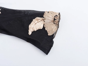 Detail van zwarte mesh mouw met prachtig goudkleurig 3D bloemeborduursel op witte achtergrond