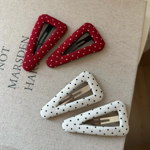 Handmade red and white polka dot fabric triangular hair clips set on textured background