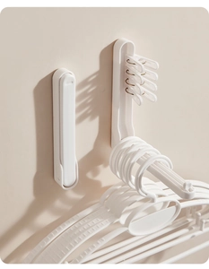 Detail of wall-mounted white folding clothes rack showing fold-up and hanging modes