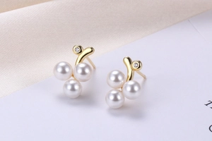 Macro view of gold pearl earrings in grape shape with small diamond and shell accents