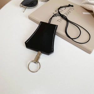 Detail of a bell-shaped black leather key holder with white stitching on a desk