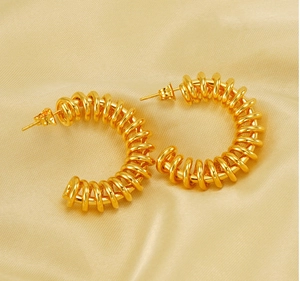 Detailed view of C-shaped spring earrings in polished gold on soft silk fabric background