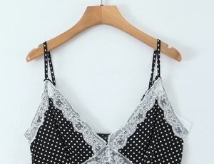Detail view of black polka dot camisole with delicate white lace trim on wooden hanger
